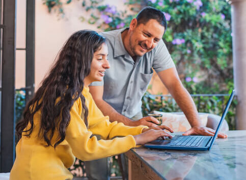 Young woman on laptop filing taxes with man looking at screen