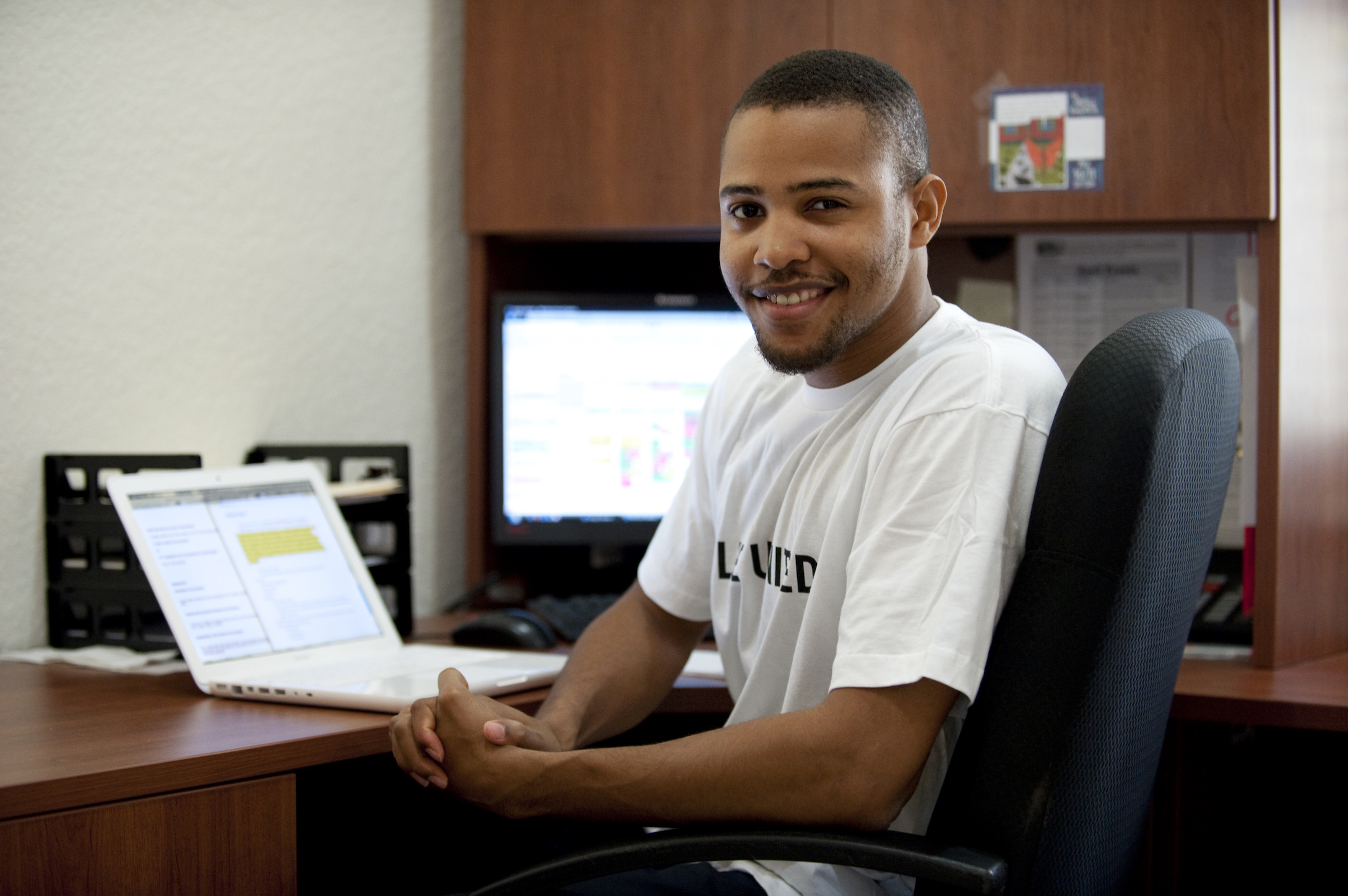 Smiling young Black man sitting next to an open laptop